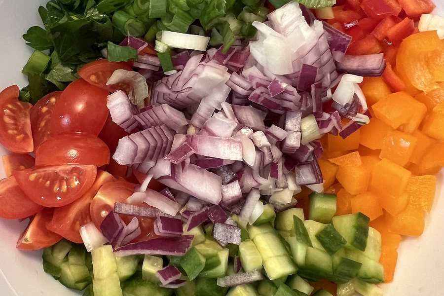 A large mixed salad with tomatoes, peppers, and fresh greens