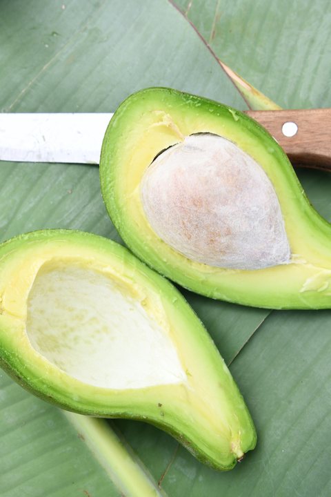 A halved avocado on a white surface