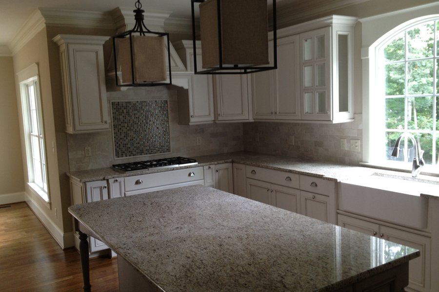 A bright white kitchen with lemons, bread, and fresh herbs on the counter